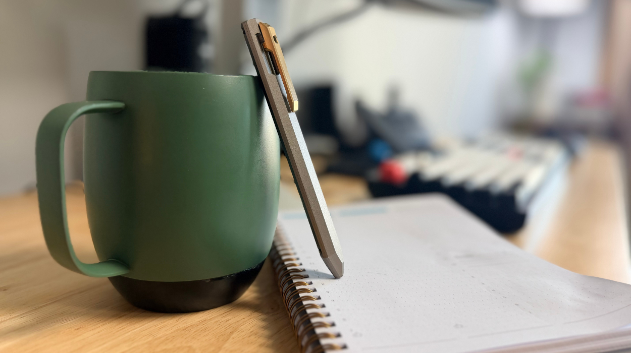 The PROOF Vanguard Pen resting against a mug upon a desk