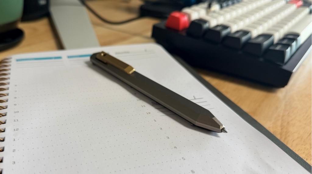 The PROOF Vanguard Pen in the “out” position resting upon a planner book